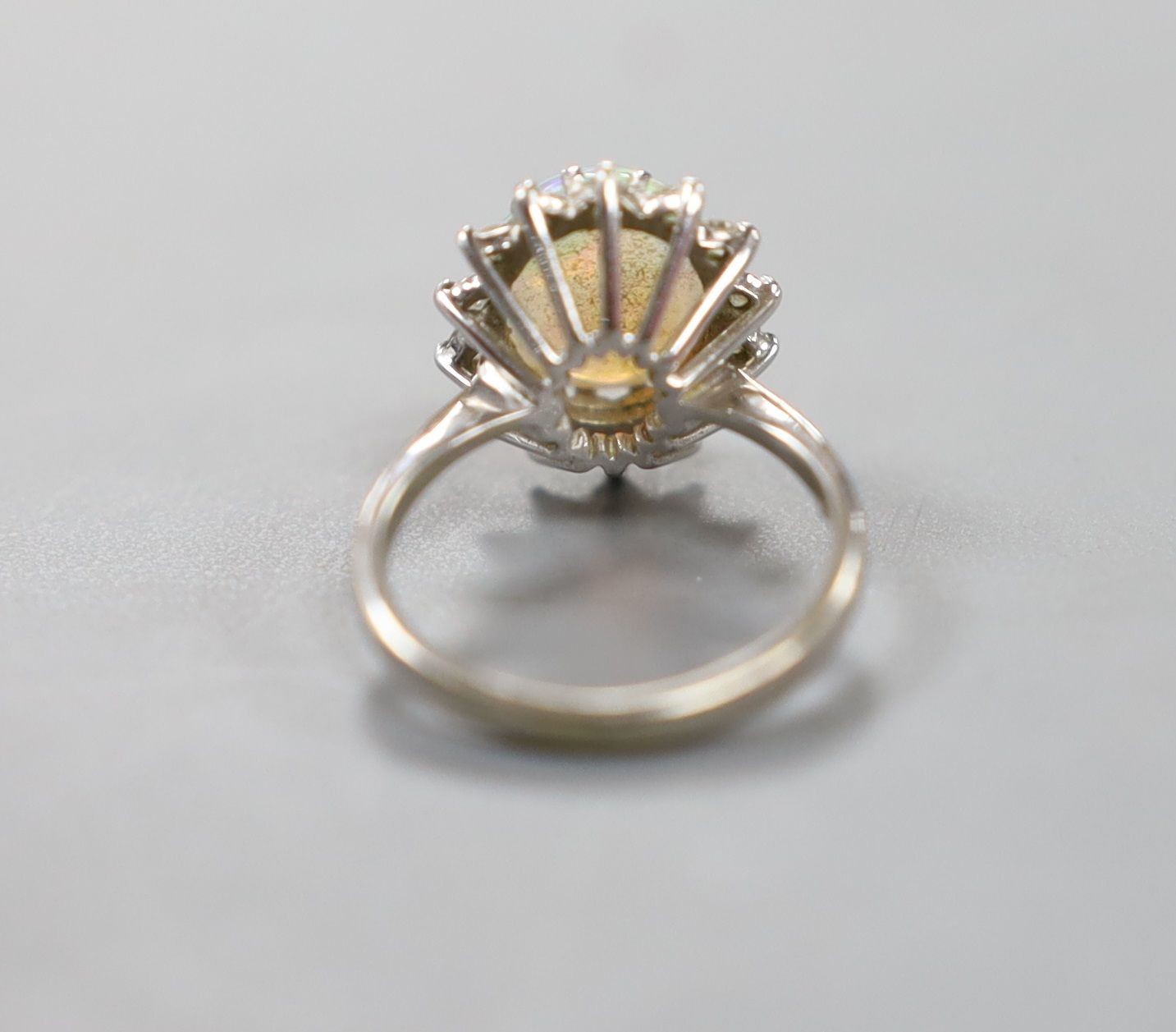 An 18ct white metal, white opal and diamond set oval cluster ring, size G, gross weight 2.9 grams.